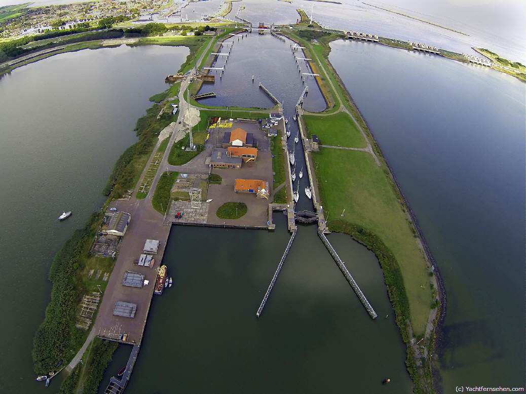 Luchtfoto/Luftbild: Stevinsluis in Den Oever von boven/von oben. Die Schleuse Den Oever am Abschlussdeich zwischen Wattenmeer und IJsselmeer aus der Vogelperspektive.